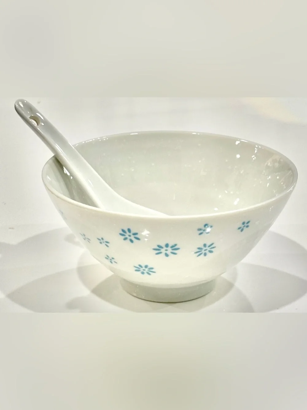White Ceramic Bowl with Blue Floral Motif on Exterior and Matching Spoon